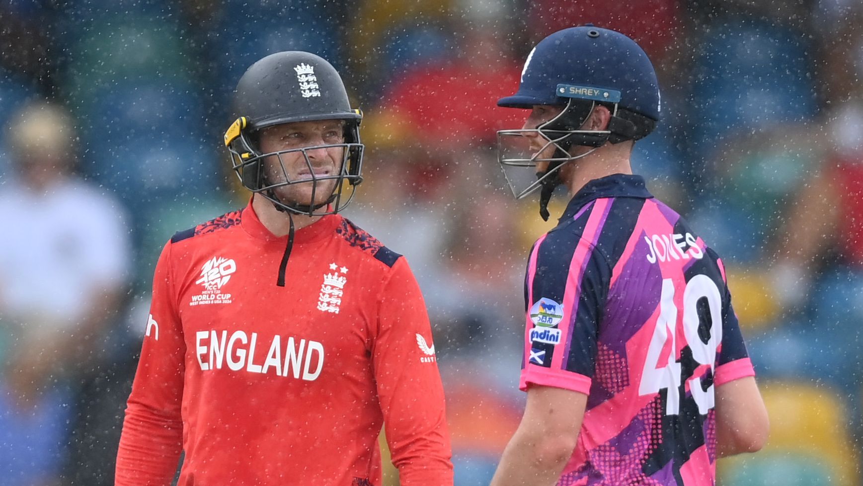Jos Buttler of England and Michael Jones of Scotland leave the field as rain stops play during the ICC Men&#x27;s T20 Cricket World Cup match at Kensington Oval.
