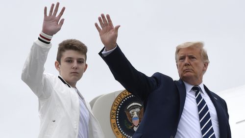 In this Aug. 16, 2020 file photo, President Donald Trump, right, and his son Barron Trump wave from the top of the steps to Air Force One at Morristown Municipal Airport in Morristown, N.J.  