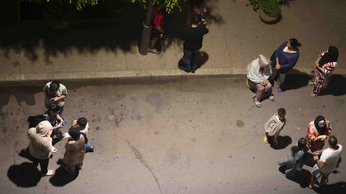 People take shelter and check for news on their mobile phones after an earthquake in Rabat, Morocco, Friday, Sept. 8, 2023. 