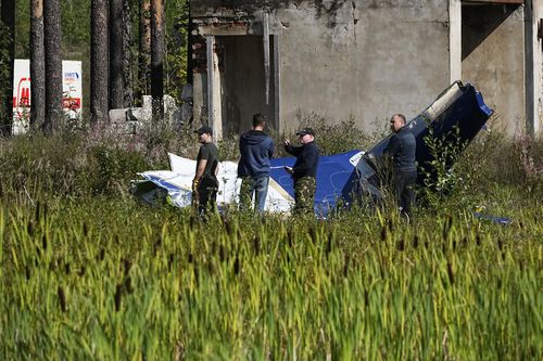 Russian servicemen inspect a part of a crashed private jet near the village of Kuzhenkino, Tver region, Russia, Thursday, Aug. 24, 2023