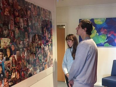 Karen shows AFL star and Rio's Legacy ambassador Billy Smith the wall of photos at Bear Cottage.