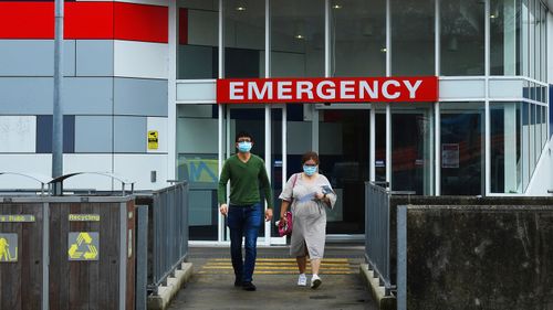 Two people wearing face masks walk out of the emergency entrance at Westmead Hospital, in Sydney's west.