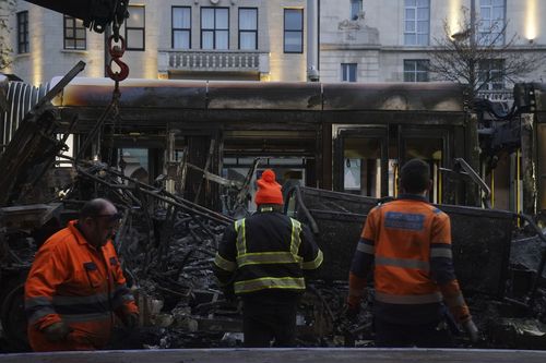 A burned out bus is removed from O'Connell Street in the aftermath of violent scenes in the city centre on Thursday evening, in Dublin, early Friday, Nov. 24, 2023.  