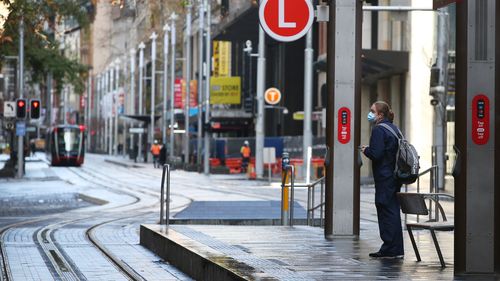 A frontline worker awaits the a tram on George Street in Sydney amid the city-wide lockdown. Sydney lockdown