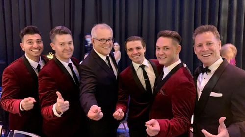 Prime Minister Scott Morrison pictured with performers Boys in the Band at the high school graduation on Friday.