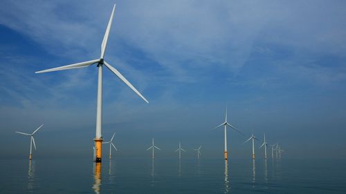 LIVERPOOL, UNITED KINGDOM - MAY 12:  Turbines of the new Burbo Bank off shore wind farm stand in a calm sea in the mouth of the River Mersey on May 12, 2008 in Liverpool, England. The Burbo Bank Offshore Wind Farm comprises 25 wind turbines and is situated on the Burbo Flats in Liverpool Bay at the entrance to the River Mersey, approximately 6.4km (4.0 miles) from the Sefton coastline and 7.2km (4.5 miles) from North Wirral. The wind farm is capable of generating up to 90MW (megawatts) of clean,