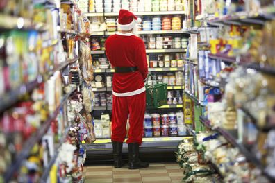 Man dressed as Santa Claus standing in supermarket, rear view - stock photo