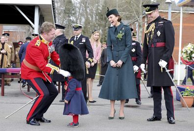 Kate, Duchess of Cambridge and Prince William laugh as Lieutenant Colonel Rob Money puts a bearskin hat on his 20-month-old daughter Gaia Money's head as they attend the 1st Battalion Irish Guards' St. Patrick's Day Parade at Mons Barracks, Thursday March 17, 2022 in Aldershot, England