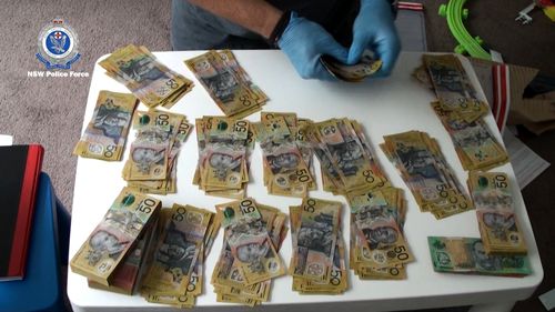 A NSW Police Officer counts cash, which allegedly totalled more than $50,000.
