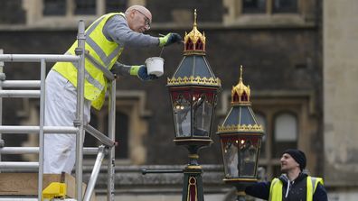 Painters repaint the lamp pots outside Westminster Abbey as preparations continue for the Coronation of King Charles III in London on Thursday, April 27, 2023.  