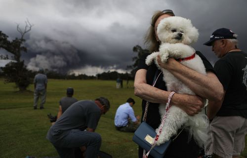 A woman picks up her dog as others watch the eruption. (Getty)