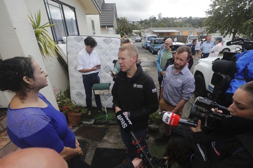 New Zealand Prime Minister Chris Hipkins, center, talks to residents affected by flooding in Auckland, Saturday, Jan. 28, 2023. 
