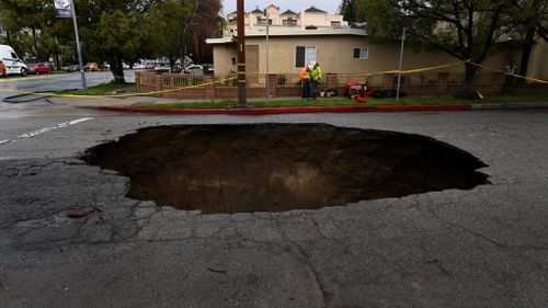 A large 6m-deep sinkhole that swallowed two vehicles in North Laurel Canyon Blvd, in Los Angeles, is cordoned-off on February 18, 2017, after a powerful storm hit southern California. (AFP)