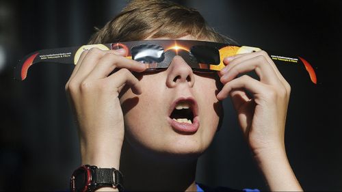 Colton Hammer tries out his new eclipse glasses he just bought from the Clark Planetarium in Salt Lake City. (AAP)