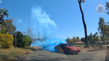 Dashcam footage shows a red Holden Commodore VP performing burnouts, with blue smoke coming from its tyres.