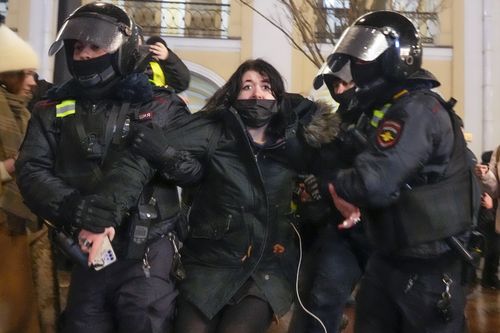 Police officers detain a woman in St. Petersburg, Russia, Friday, Feb. 25, 2022. Shocked Russians turned out by the thousands Thursday to decry their country's invasion of Ukraine as emotional calls for protests grew on social media. Some 1,745 people in 54 Russian cities were detained, at least 957 of them in Moscow. (AP Photo/Dmitri Lovetsky)