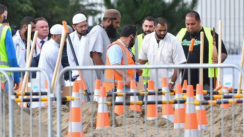 Mourners shovel dirt at the funeral of father and son, Khaled and Hamza Mustafa, the first funerals of the 50 victims of the mosque shootings, at the Memorial Park Cemetery in Christchurch.