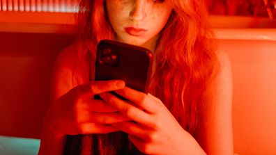 Woman cried looking at her phone in a red room.