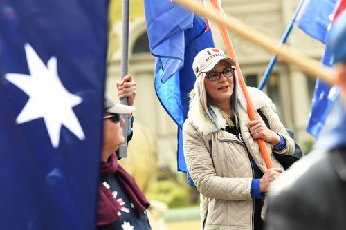 A woman totes a large Australian flag. (AAP)