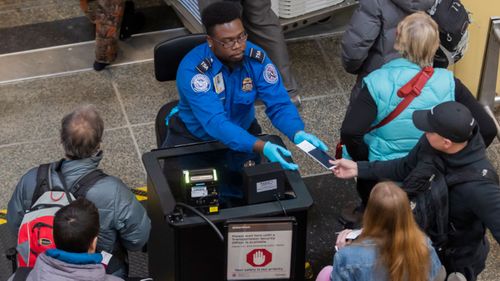 A Transportation Security Agency (TSA) agent checks the identification of air travelers at Ronald Reagan Washington National Airport as the partial shutdown drags on.