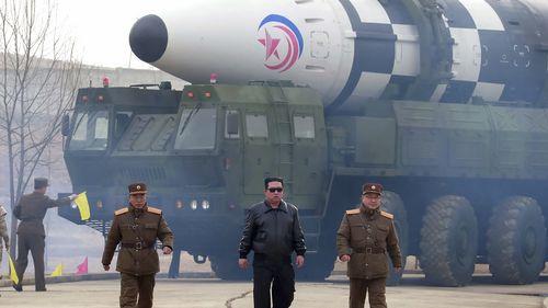 North Korean leader Kim Jong Un, center, walks around the alleged Hwasong-17 intercontinental ballistic missile. 