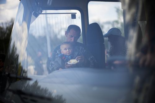 A man feeds a child as they arrive by bus at a reception center for displaced people in Zaporizhzhia, Ukraine, Monday, May 2, 2022. Thousands of Ukrainian continue to leave Russian occupied areas. (AP Photo/Francisco Seco)