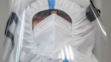 A volunteer of German Red Cross DRK wears protective gear as he waits in a mobile coronavirus test station for travellers from foreign countries.