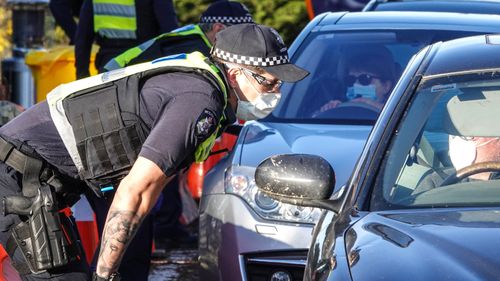 Victoria Police members stop motorists leaving metropolitan Melbourne at a checkpoint set up on the on the Calder Freeway