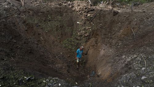 A resident walks into a crater caused by a missile strike in Druzhkivka, eastern Ukraine, Sunday, June 5, 2022. (AP Photo/Bernat Armangue)