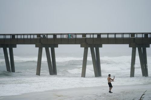 A person takes a photo at Navarre Beach, Tuesday, Sept. 15, 2020, in Pensacola Beach, Fla. Hurricane Sally is crawling toward the northern Gulf Coast at just 2 mph, a pace that's enabling the storm to gather huge amounts of water to eventually dump on land. (AP Photo/Gerald Herbrt)
