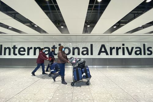 Passengers walk at the International Arrivals at Hearhtow Airport, in London, Friday, Nov. 26, 2021. 