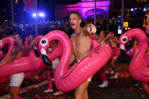 Men march in pink flamingo pool toys. (AAP)