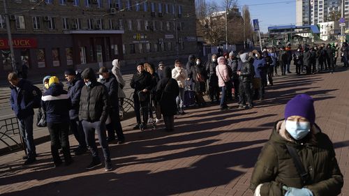 People wait in a queue outside a supermarket in central Kyiv, Ukraine after a weekend curfew ended.