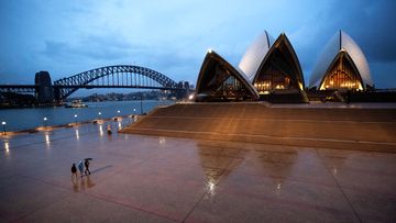 People walk on the forecourt of the Sydney Opera House. Sydney is deserted as people stay home because of the coronavirus and social distancing measures.