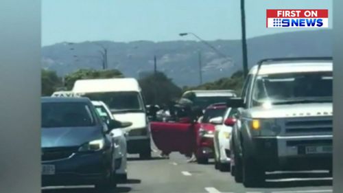 The man can be seen charging at the car as other drivers attempt to restrain him. (9NEWS)