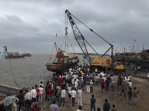 People use a crane to pull a fishing boat ashore on the Arabian Sea coast in Veraval. (Ajit Solanki)