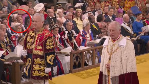 King Charles stands in Westminster Abbey during his coronation. Prince Harry can be seen in the background.