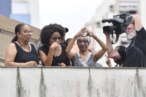 Maria Lucia Nascimento, the sister of the late Brazilian soccer great Pele, signals a heart to people gathered outside her mother's home, during Pele's funeral procession from Vila Belmiro stadium to the cemetery in Santos, Brazil, Tuesday, Jan. 3, 2023. 