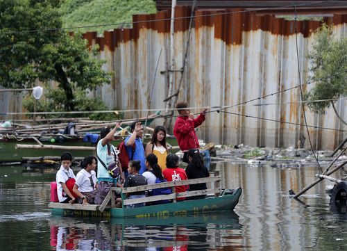 Residents on a makeshift boat make for safer areas of the capital Manila.