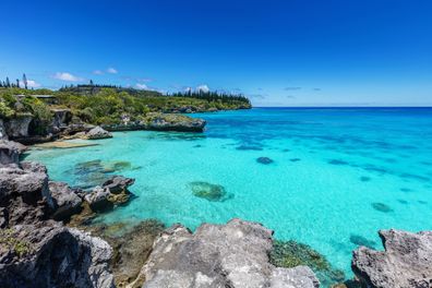 View over turquoise lagoon, south coast of Maré Island with beautiful natural rocky lagoon and coral reef to the horizon under sunny blue summer sky. Mare Island, Loyalty Islands, New Caledonia, Pacific Ocean Islands.