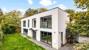 Modern white rectangular two-storey house with green lawn. 