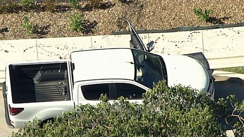 Vision from the crime scene shows a trail of blood on a footpath next to a while dual-cab ute with the door still open.