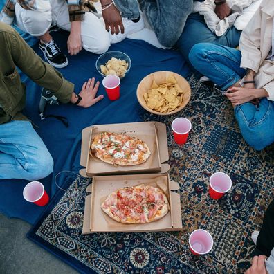 Stock image of friends eating pizza, chips and beer.