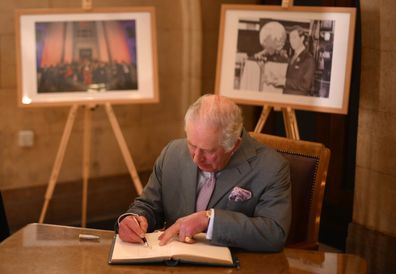 King Charles III signs the visitors' book as he visits Luton Town Hall on December 6, 2022 in Luton, England