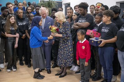 King Charles III looks on as Camilla, the Queen Consort receives a bouquet of flowers as they visit Project Zero in Walthamstow, East London, Tuesday, Oct. 18, 2022.
