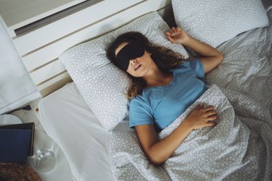 An attractive young woman sleeping with a mask on her face in her bedroom at home