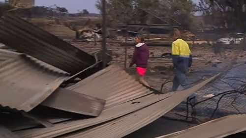 Mr and Mrs Moss inspect their fire-damaged property. (9NEWS)