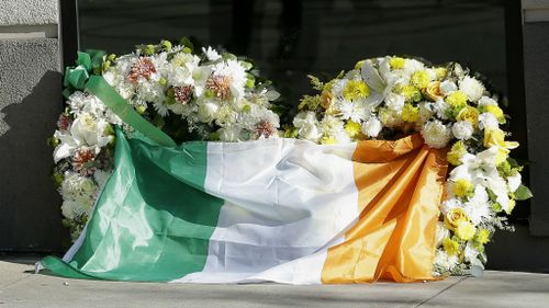 A flag of Ireland is draped over wreaths at the Library Gardens apartment complex in Berkeley. (AAP)