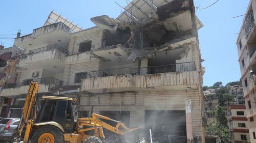 A bulldozer clears rubble near a destroyed building that was hit in an Israeli airstrike in Nabatieh town, south Lebanon, Friday, June 27, 2025. (AP Photo/Mohammed Zaatari)