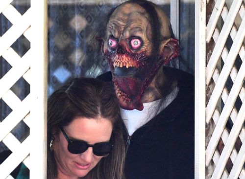 A masked man lets a woman out of the home of Schapelle Corby's mother. (AAP)